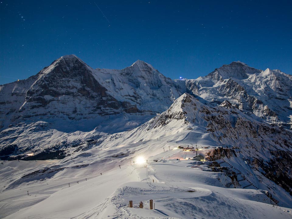 Die schneebedeckte Skipiste des Berges Männlichen im Skigebiet Grindelwald liegt unter einem Sternenhimmel